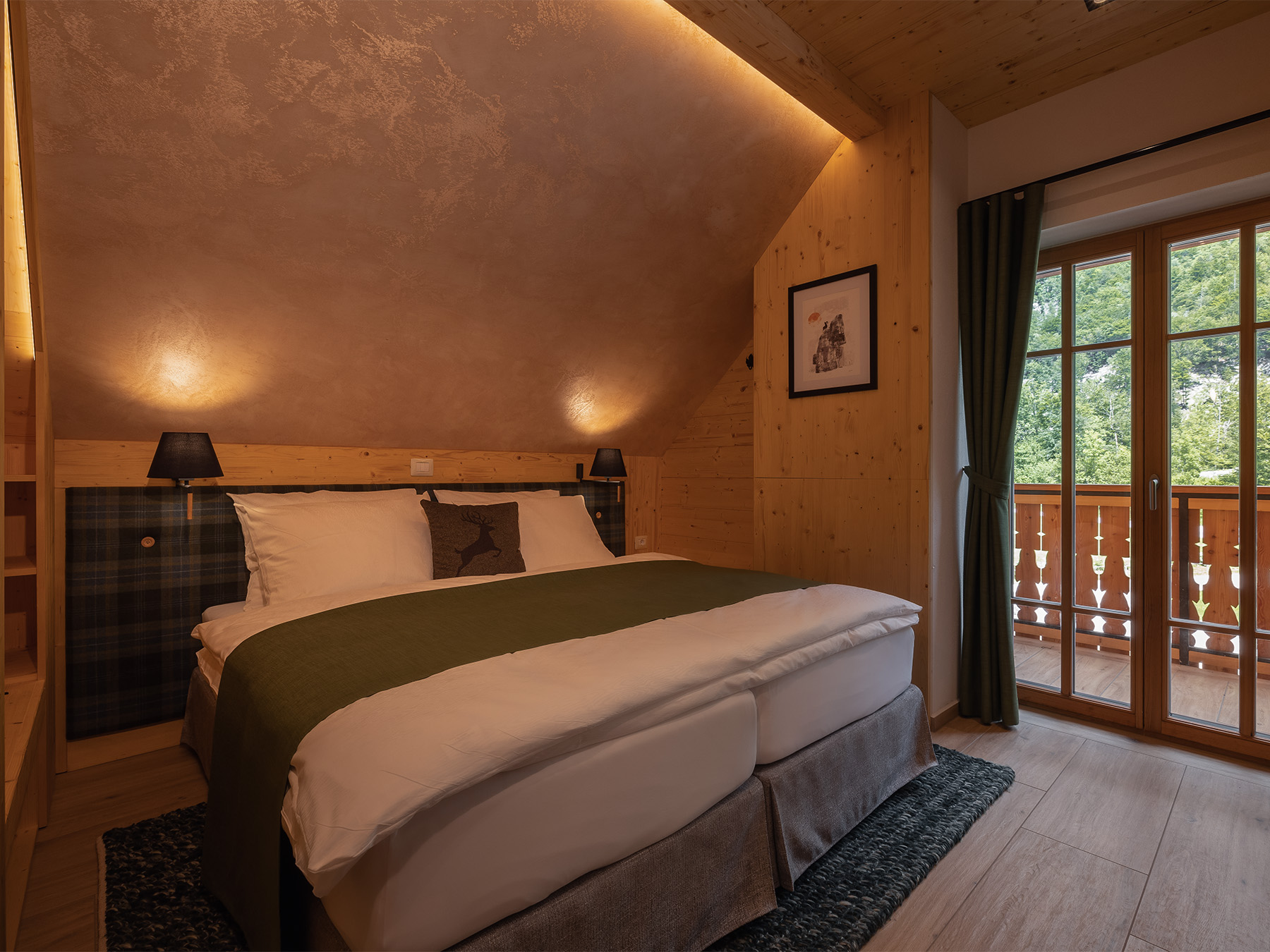 Bedroom inside the Alpine SPA Chalet with natural wood, green textiles and balcony doors.