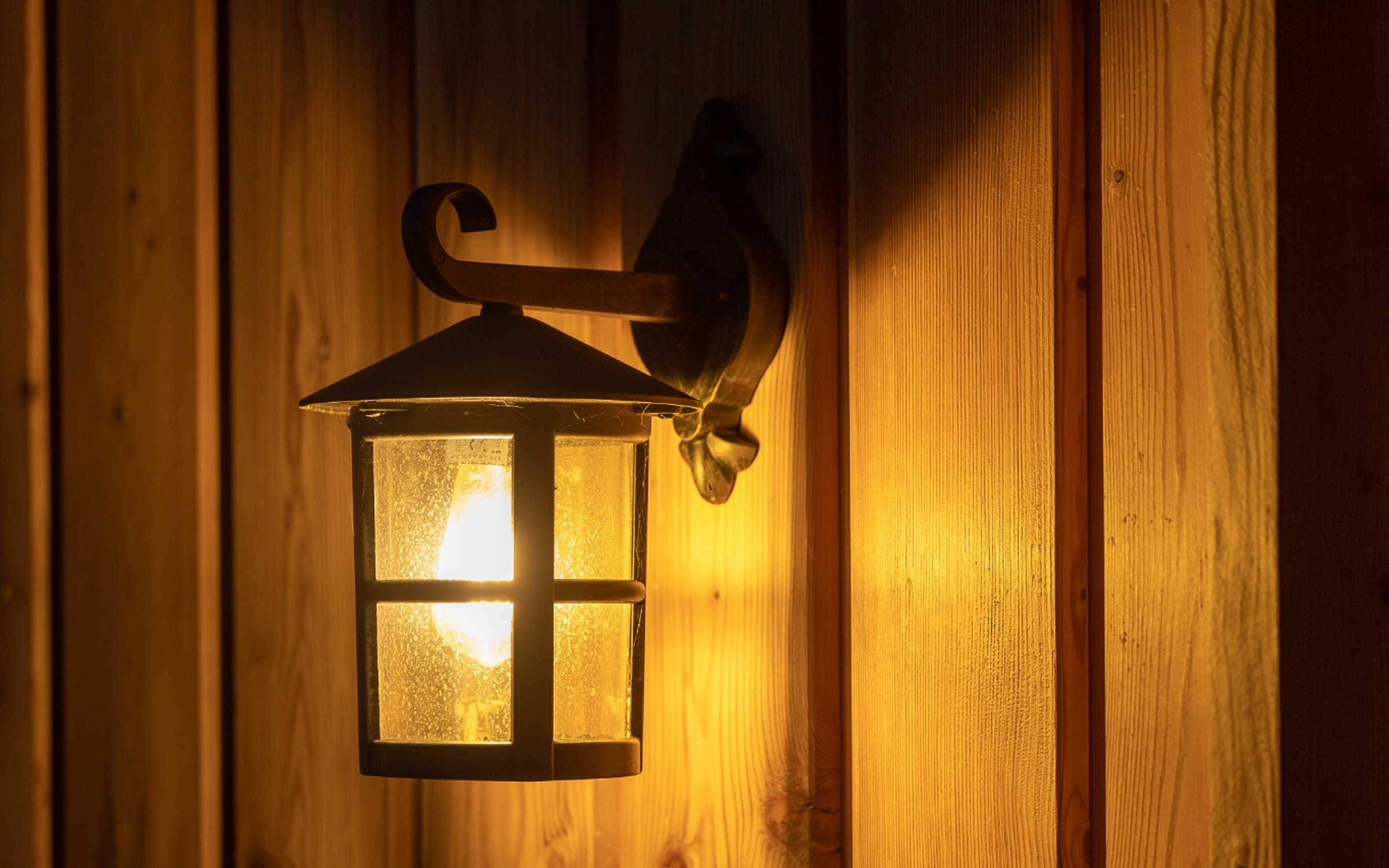 Warm exterior lantern glowing against the wooden facade of the Alpine SPA Chalet.