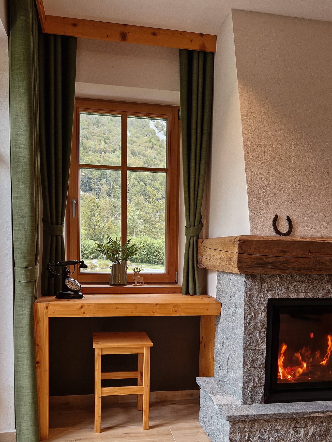 Fireplace beside a window overlooking the forest inside the Alpine SPA Chalet by Lake Bohinj.