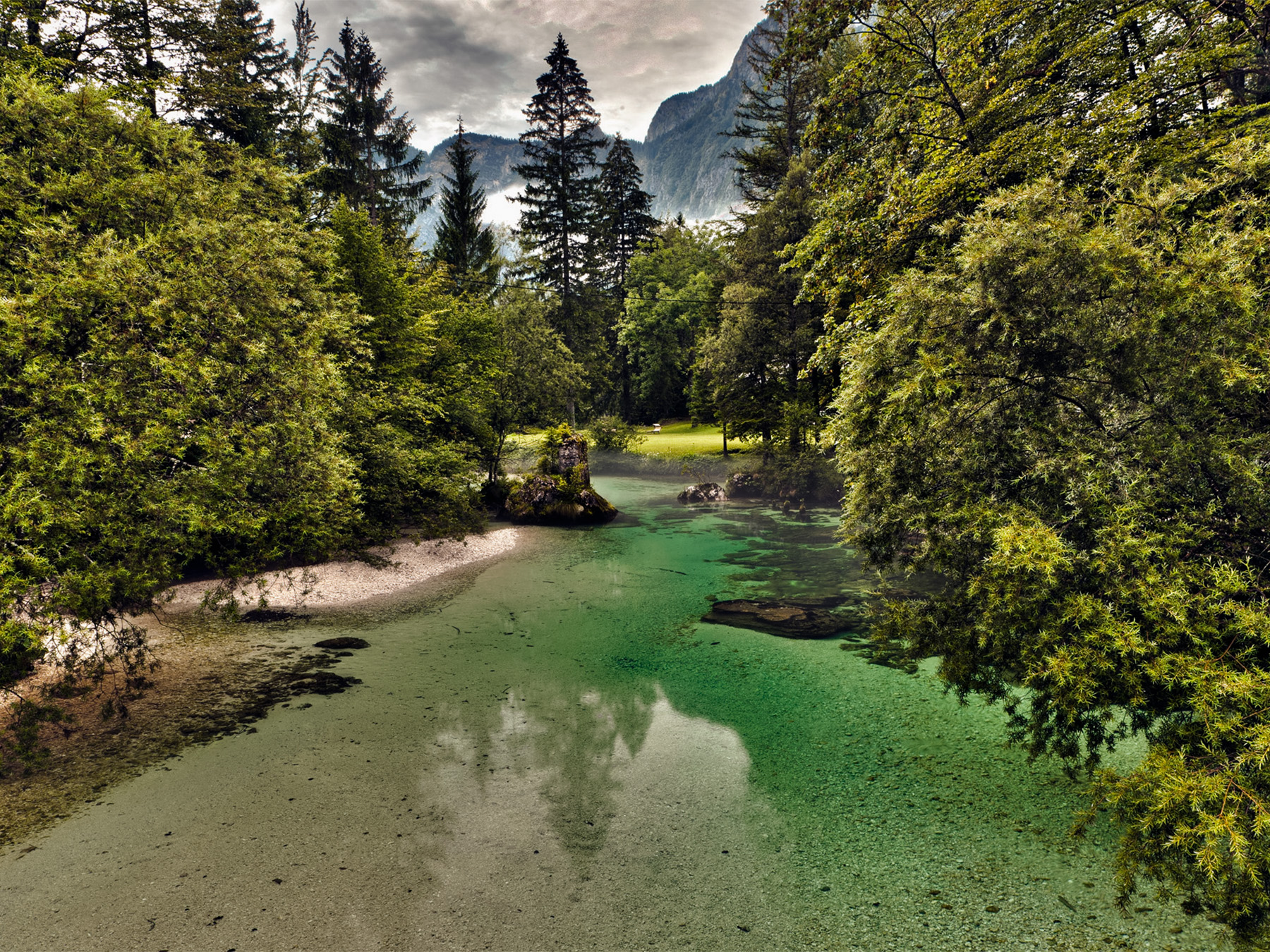 Savica River flowing through the forest in Ukanc with the Julian Alps rising in the background.