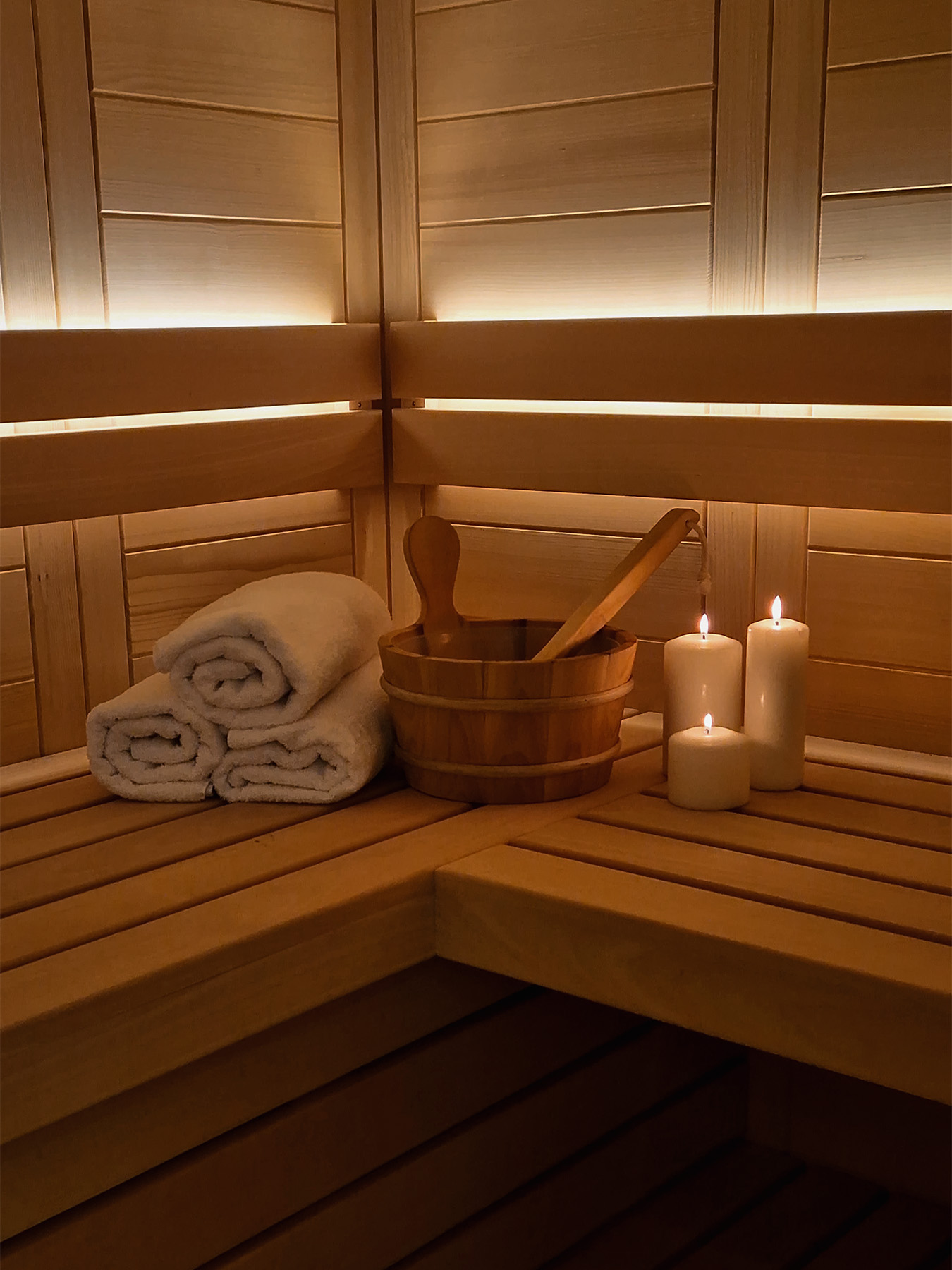 Finnish sauna with folded towels, wooden bucket and candlelight in the private wellness area of an Alpine SPA Chalet.