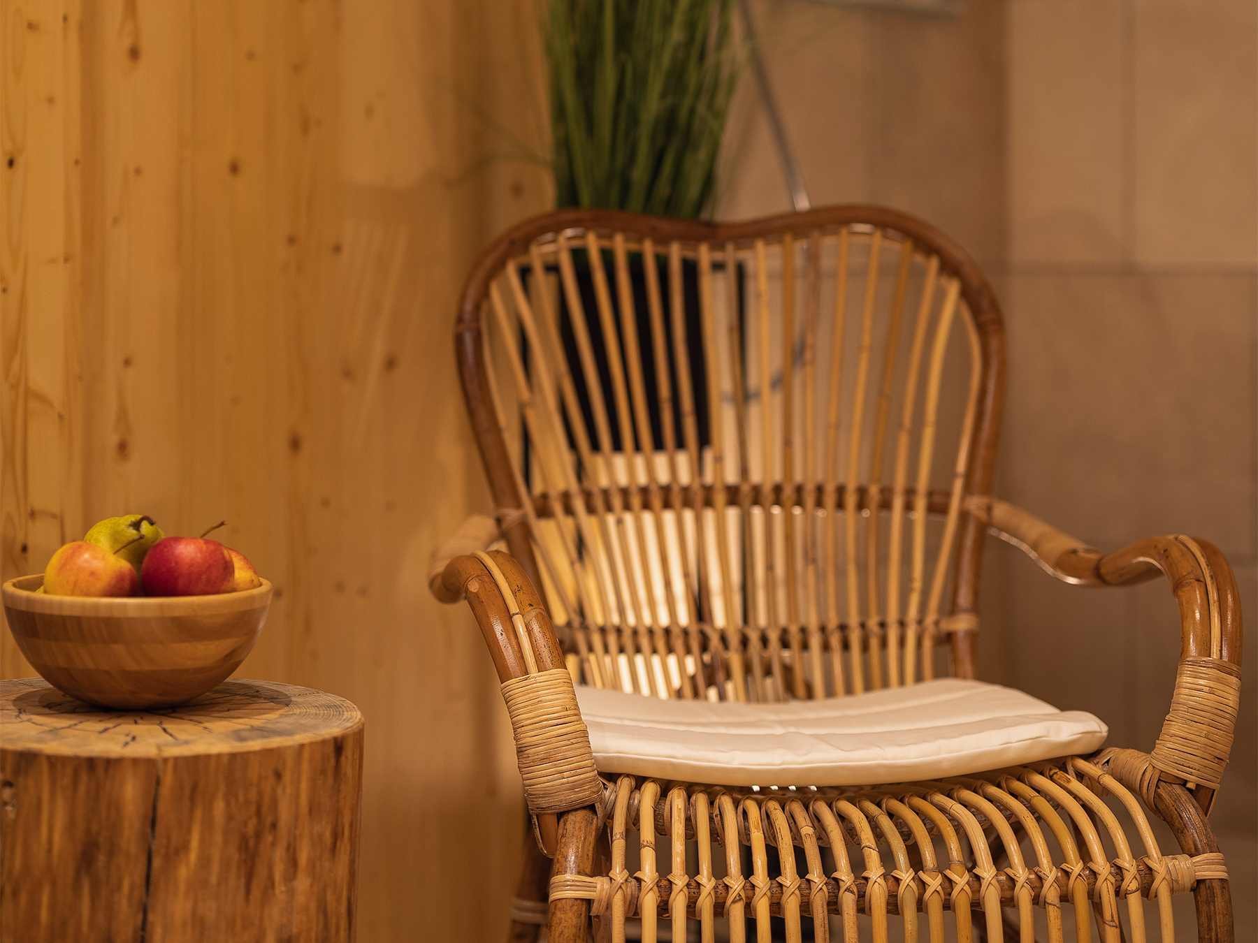 Rattan chair beside a wooden table with fresh fruit in the private wellness area of the Alpine SPA Chalet by Lake Bohinj.